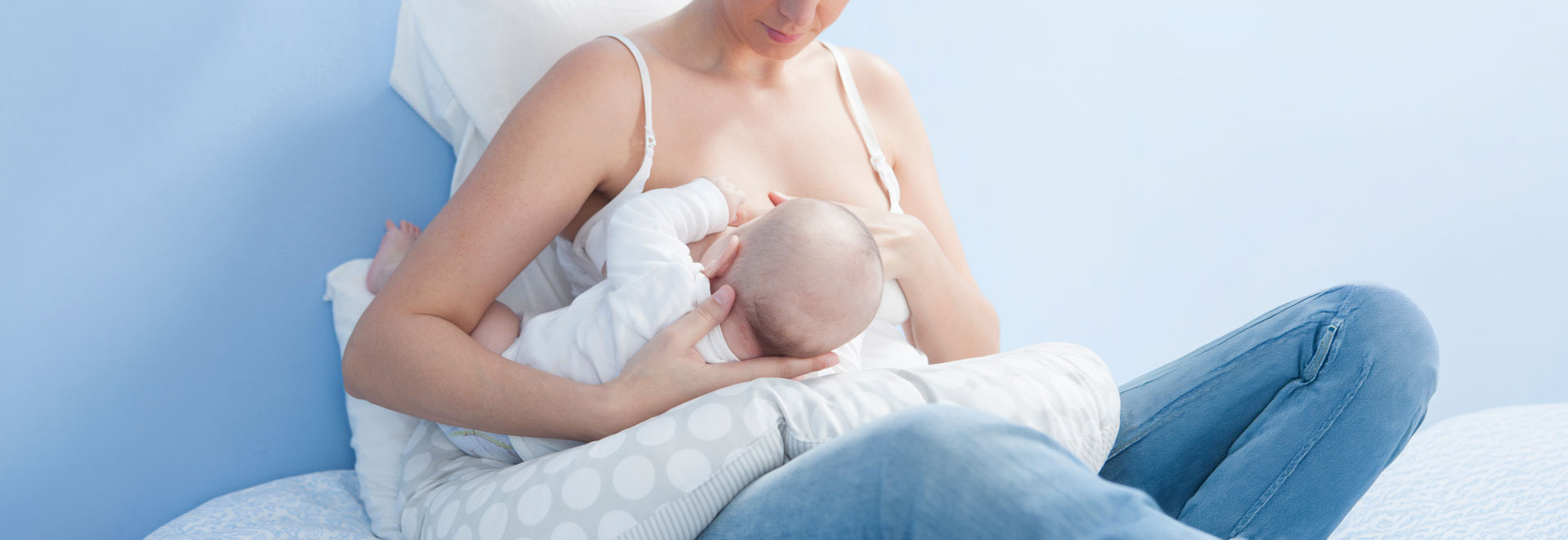 Mother breastfeeding baby with nursing pillow