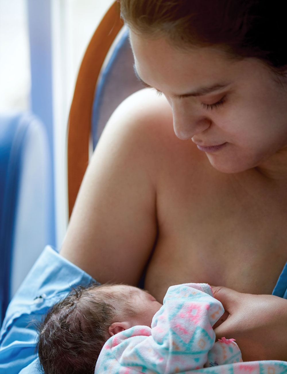 Mother looking down at her newborn while breastfeeding
