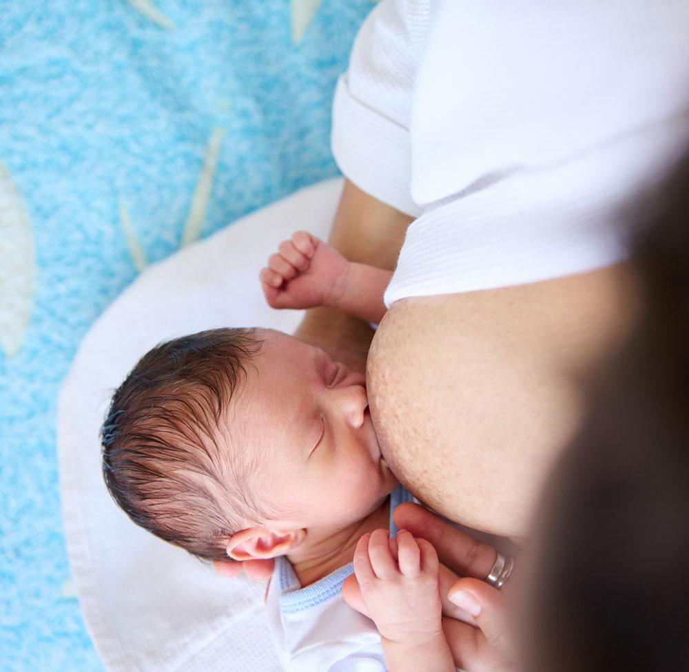 Newborn baby breastfeeding from above view