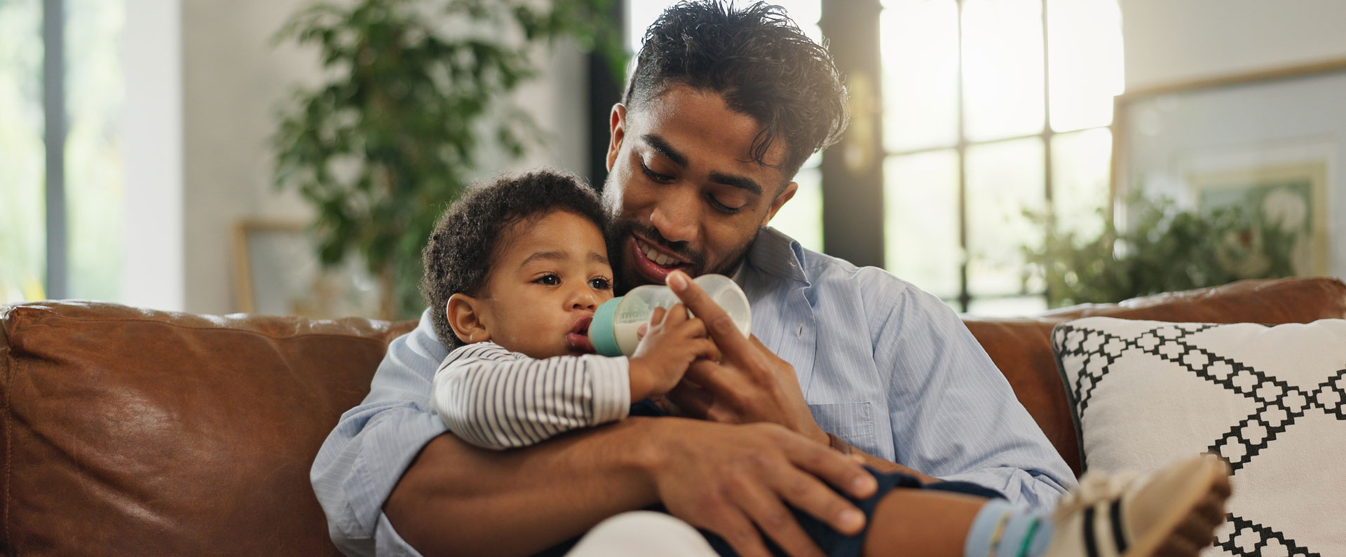 father-feeding-baby-with-a-bottle-on-the-couch