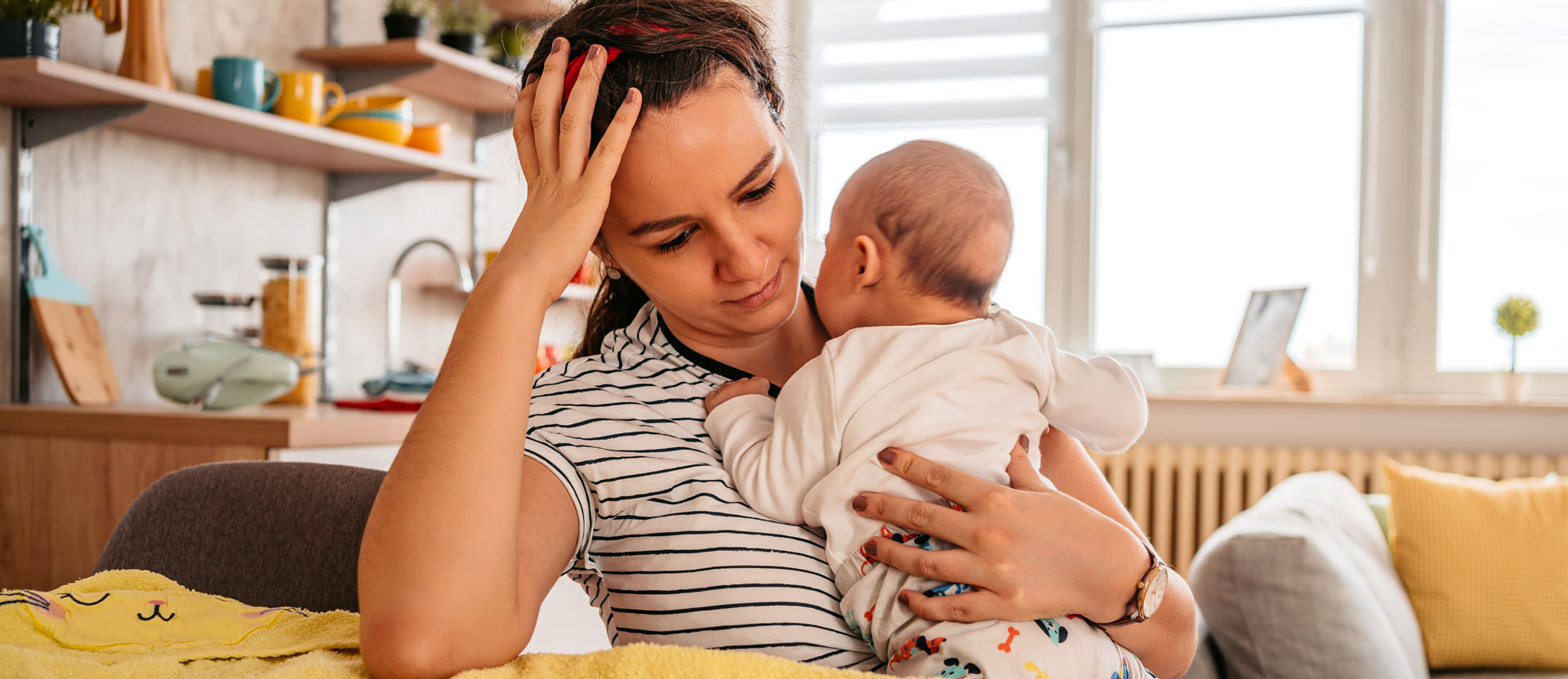 A tired mother holding her newborn baby in her arms at home