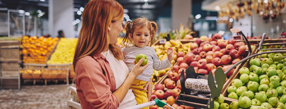 A woman and a child smile while grocery shopping