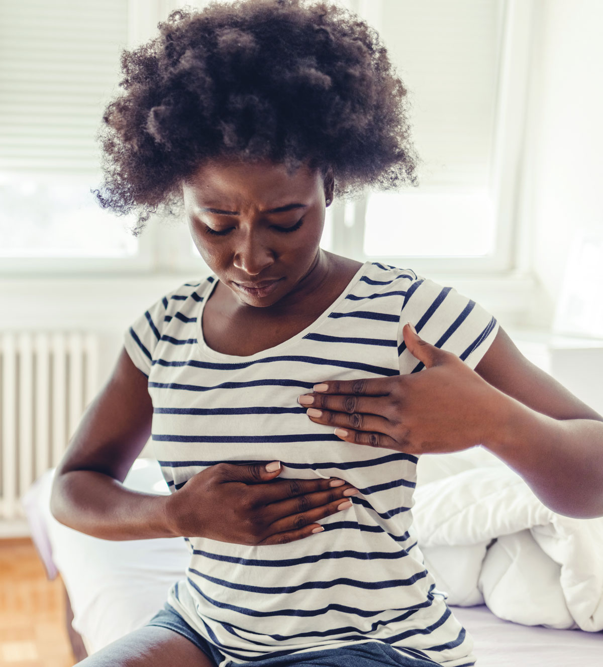 Woman performing a breast self-exam to check for changes or discomfort.
