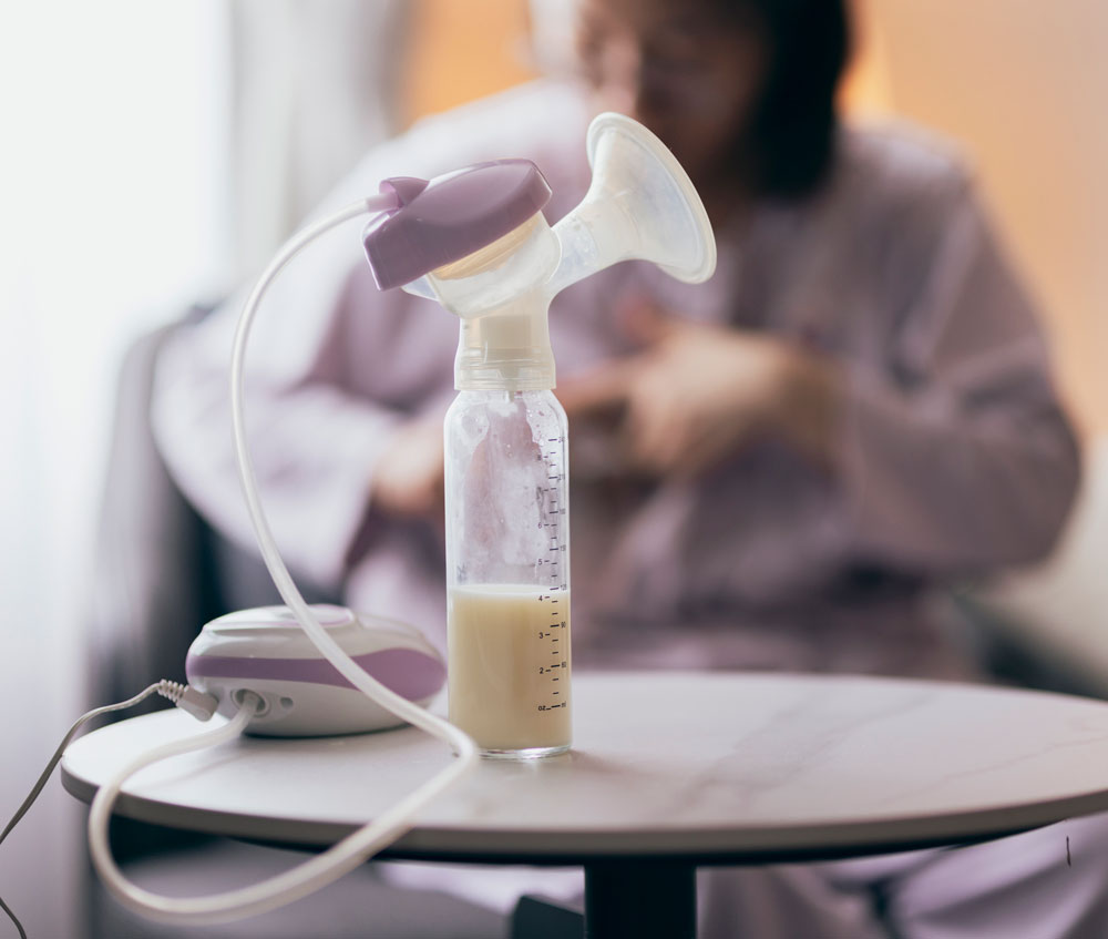 Breast pump and expressed milk bottle on table