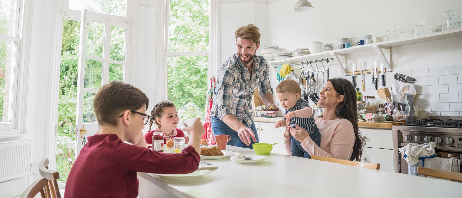 Family gathered around table for breakfast, smiling together