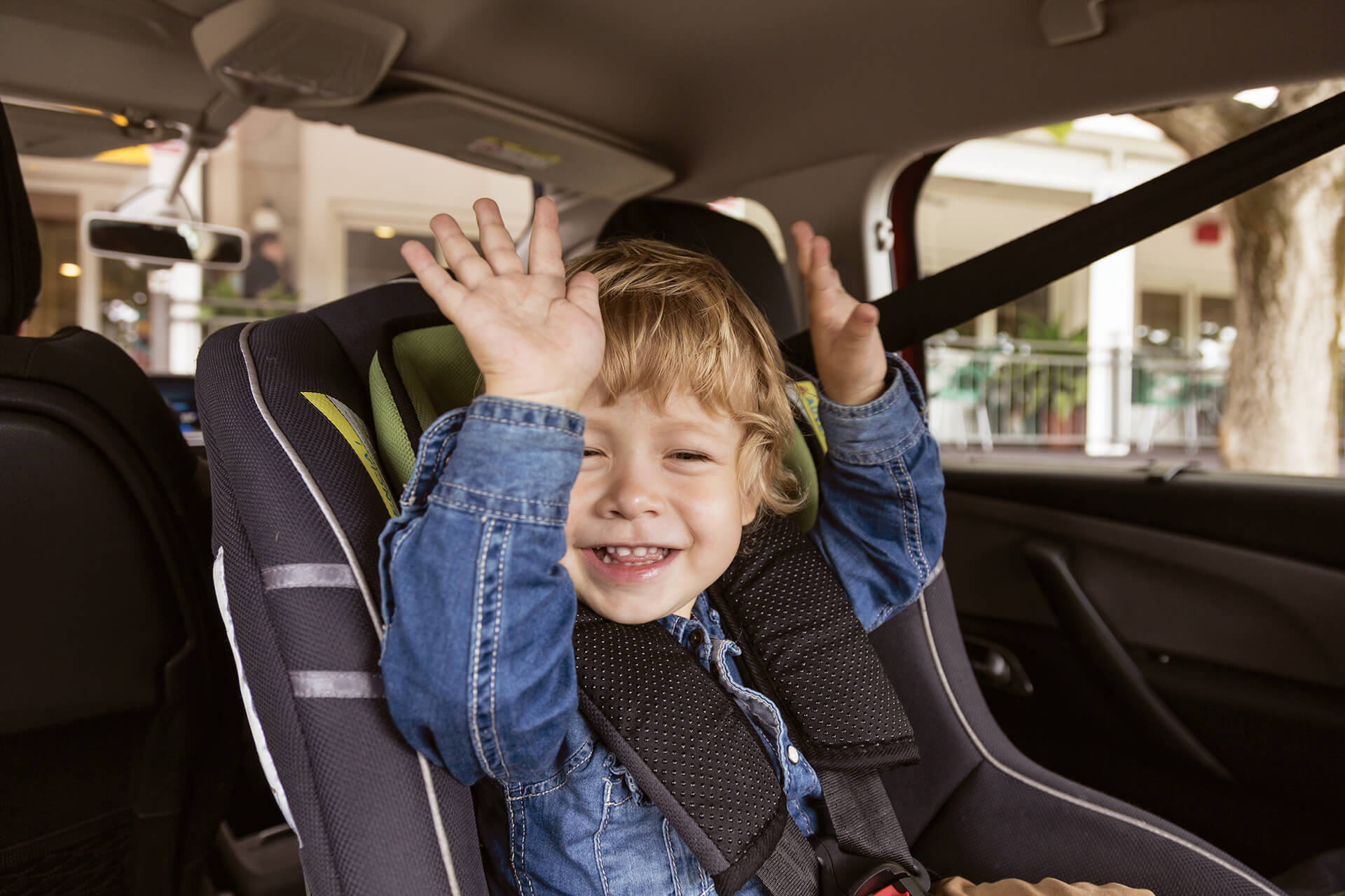 A toddler sitting in a car seat, possibly looking out of the window or resting comfortably.