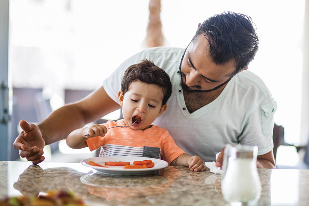 A father and son sitting together at a table, eating a meal.