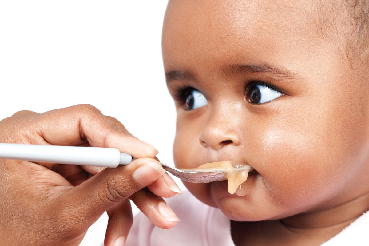 Image of baby feeding using spoon