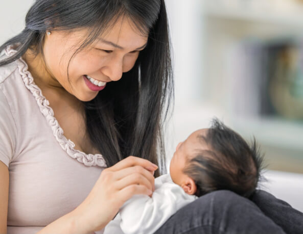 A mother holding her baby close while smiling warmly.