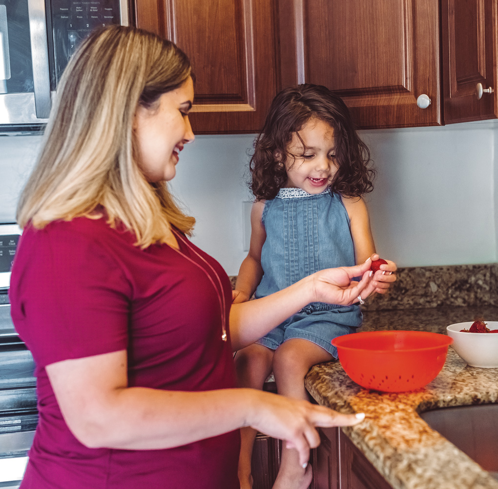 A mother and daughter in the kitchen, likely preparing food or engaging in a cooking activity together.