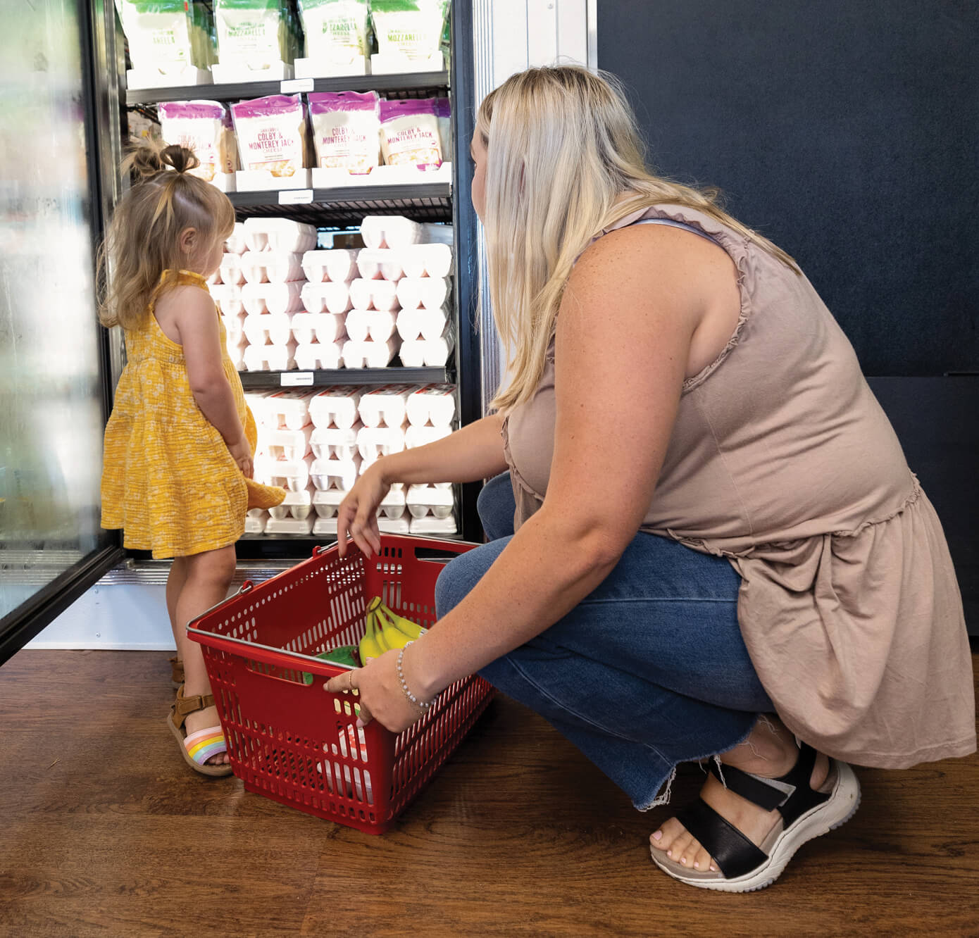 Woman and child selecting eggs in grocery store.