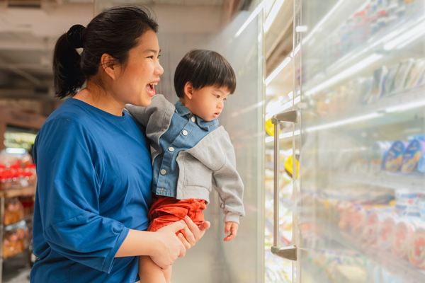 Mother holding child, looking at grocery store shelves
